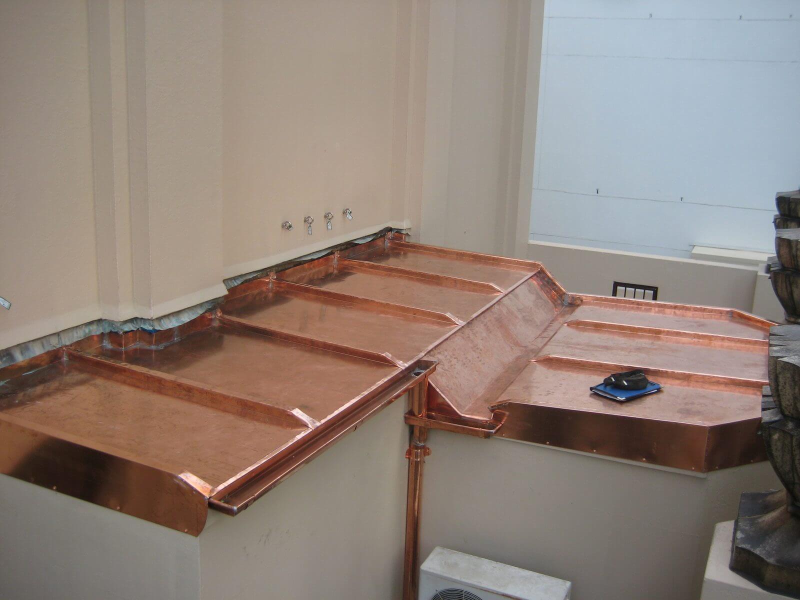 Custom copper roof and downpipe wrapping a building corner