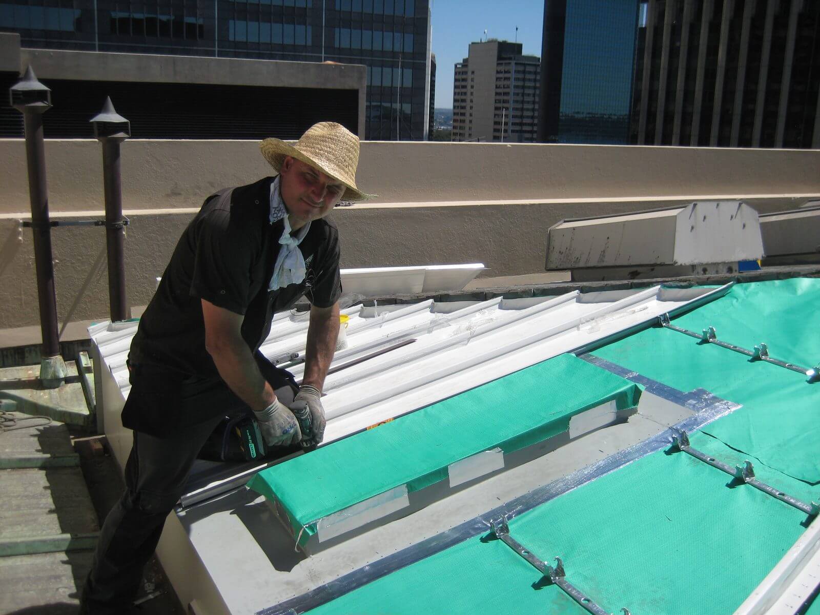 Jeremy Williams fixing custom metal roofing sheets on a city rooftop