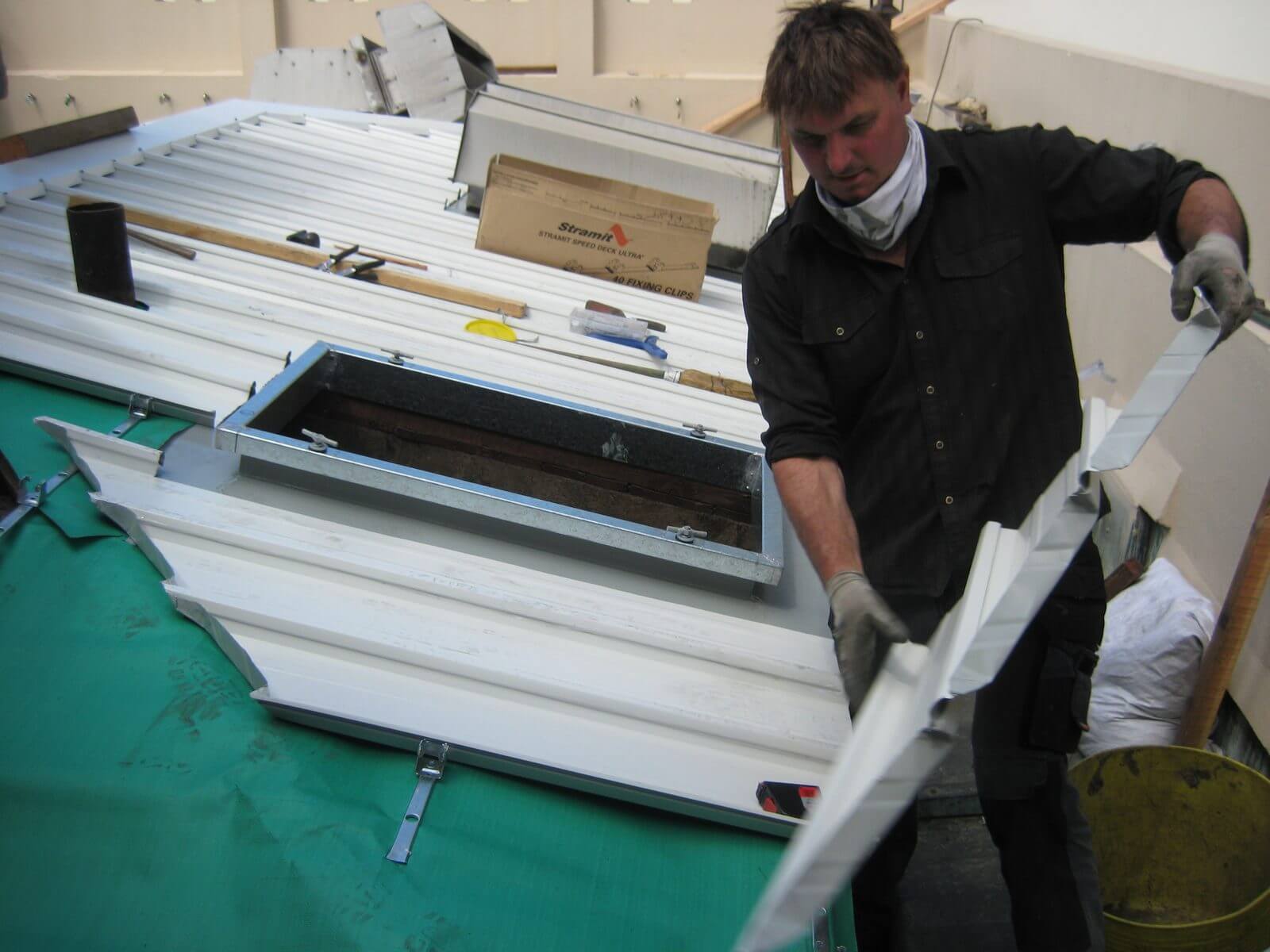 Jeremy Williams fitting a custom metal roofing panel into place