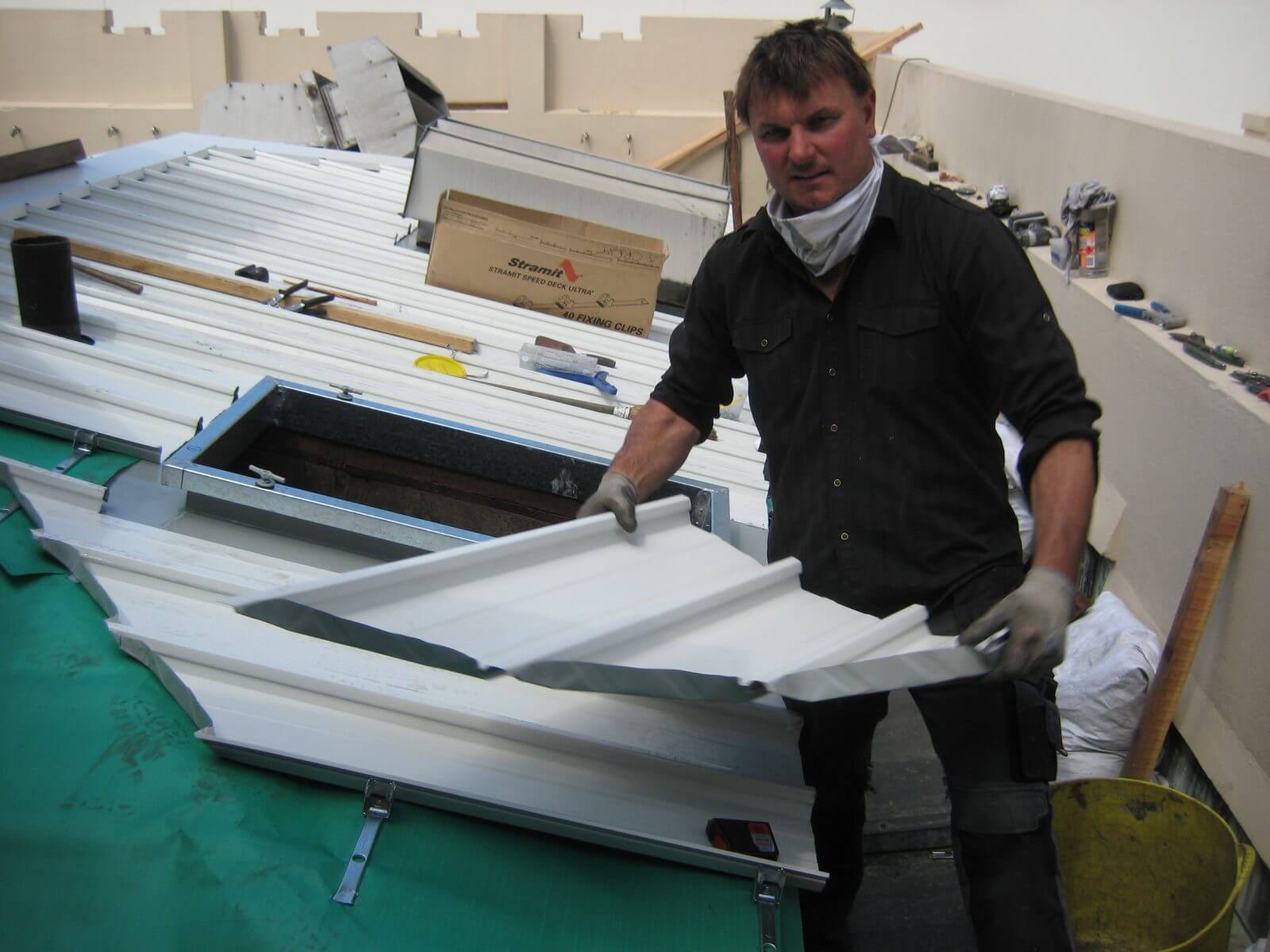 Jeremy Williams holding a custom metal roofing panel over an open roof penetration