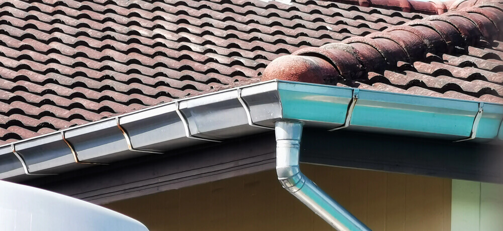 New metal gutter and downpipe on a tiled roof
