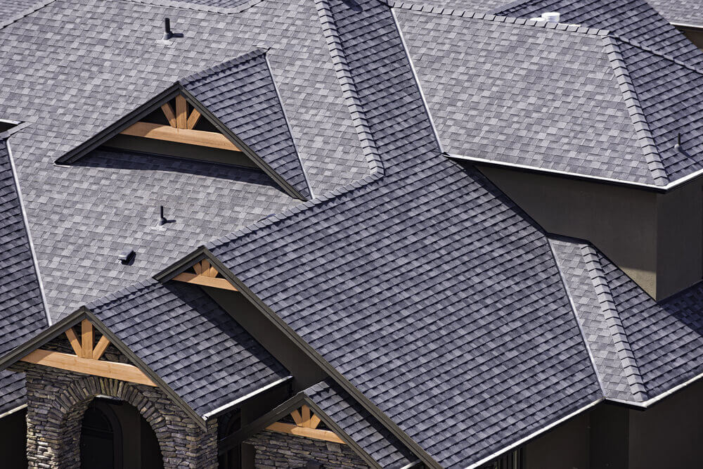 Finished residential roof with grey shingles and timber gable details